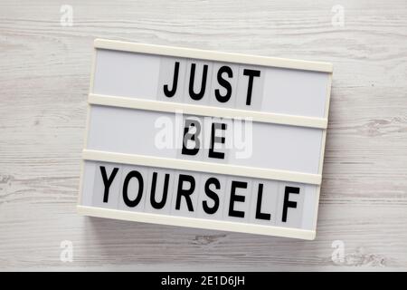 "Just be yourself" su un lightbox su sfondo bianco di legno, vista dall'alto. Posa piatta, sovratesta, dall'alto. Foto Stock