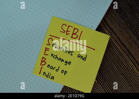 SEBI - Securities and Exchange Board of India scrivere su note appiccicose isolate su tavola di legno. Foto Stock