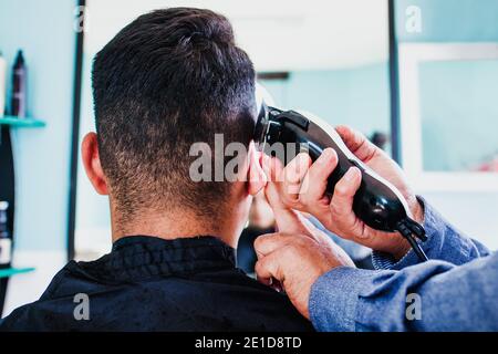 latin Barber Shop, barbiere messicano che taglia i capelli con un regolacapelli o rasoio a Città del Messico Foto Stock