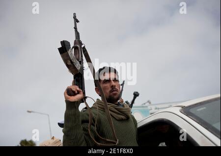 Il 7 marzo 2011 un ribelle tiene la sua pistola Kalashnikov all'ingresso della città petrolifera di Ras Lanouf, Libia orientale. Oggi le armi da fuoco libiche in elicottero hanno sparato sulle forze ribelli. La forza di opposizione anti-Gheddafi assicurò il controllo di due importanti porti petroliferi a Brega e Ras Lanouf. Foto di Arnaud Finistre/ABACAPRESS.COM Foto Stock