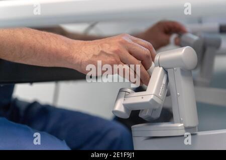 un chirurgo manipola i comandi di un robot che funziona un paziente Foto Stock