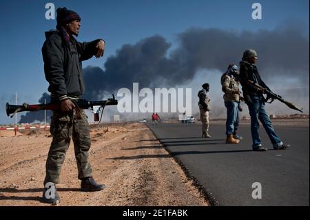 I ribelli libici sono visti combattere le forze governative come un impianto petrolifero danneggiato brucia a Ras Lanuf, Libia, il 11 marzo 2011. Le forze fedeli al leader libico Moammar Gheddafi hanno spinto le forze di opposizione fuori dalla strategica città petrolifera, costringendo un frenetico ritiro dei ribelli attraverso il deserto. Foto di Arnaud Finistre/ABACAPRESS.COM Foto Stock