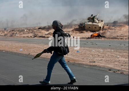 I ribelli libici sono visti combattere le forze governative come un impianto petrolifero danneggiato brucia a Ras Lanuf, Libia, il 11 marzo 2011. Le forze fedeli al leader libico Moammar Gheddafi hanno spinto le forze di opposizione fuori dalla strategica città petrolifera, costringendo un frenetico ritiro dei ribelli attraverso il deserto. Foto di Arnaud Finistre/ABACAPRESS.COM Foto Stock