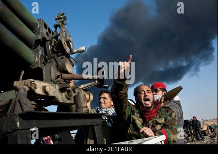 I ribelli libici sono visti combattere le forze governative come un impianto petrolifero danneggiato brucia a Ras Lanuf, Libia, il 11 marzo 2011. Le forze fedeli al leader libico Moammar Gheddafi hanno spinto le forze di opposizione fuori dalla strategica città petrolifera, costringendo un frenetico ritiro dei ribelli attraverso il deserto. Foto di Arnaud Finistre/ABACAPRESS.COM Foto Stock