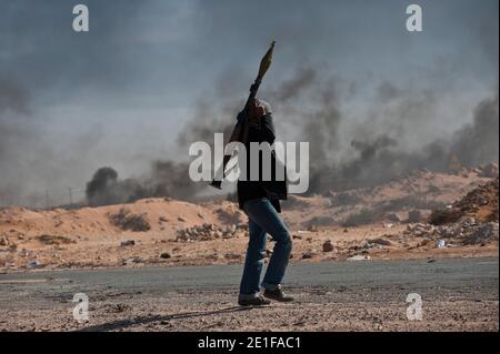 I ribelli libici sono visti combattere le forze governative come un impianto petrolifero danneggiato brucia a Ras Lanuf, Libia, il 11 marzo 2011. Le forze fedeli al leader libico Moammar Gheddafi hanno spinto le forze di opposizione fuori dalla strategica città petrolifera, costringendo un frenetico ritiro dei ribelli attraverso il deserto. Foto di Arnaud Finistre/ABACAPRESS.COM Foto Stock