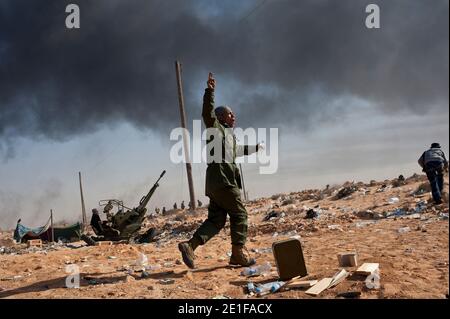 I ribelli libici sono visti combattere le forze governative come un impianto petrolifero danneggiato brucia a Ras Lanuf, Libia, il 11 marzo 2011. Le forze fedeli al leader libico Moammar Gheddafi hanno spinto le forze di opposizione fuori dalla strategica città petrolifera, costringendo un frenetico ritiro dei ribelli attraverso il deserto. Foto di Arnaud Finistre/ABACAPRESS.COM Foto Stock