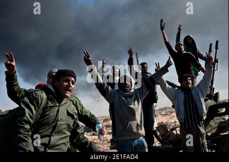 I ribelli libici sono visti combattere le forze governative come un impianto petrolifero danneggiato brucia a Ras Lanuf, Libia, il 11 marzo 2011. Le forze fedeli al leader libico Moammar Gheddafi hanno spinto le forze di opposizione fuori dalla strategica città petrolifera, costringendo un frenetico ritiro dei ribelli attraverso il deserto. Foto di Arnaud Finistre/ABACAPRESS.COM Foto Stock