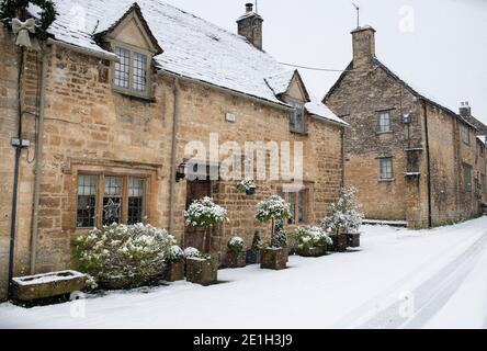 Cotswold case in pietra nella neve in Witney Street a natale. Burford, Cotswolds, Oxfordshire, Inghilterra Foto Stock