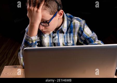 Ragazzo con gli occhiali e la camicia sul laptop di apprendimento bruciare fuori Foto Stock