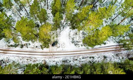 Vista aerea della Black Car sulla strada forestale coperta dalla neve Foto Stock