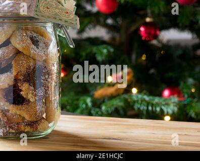 Biscotti di Natale in un vaso di vetro su un tavolo con albero di natale sullo sfondo Foto Stock