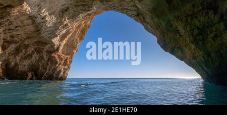 Una vista panoramica dall'interno di una grotta sull'oceano costa con acque turchesi e cielo azzurro soleggiato all'esterno Foto Stock