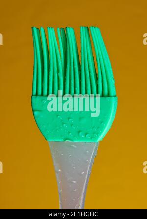 Spazzola per cucina in silicone per cucinare in gocce d'acqua sfondo giallo Foto Stock