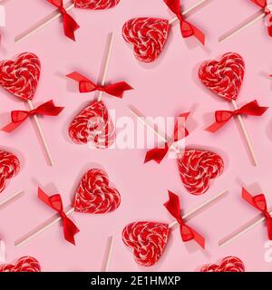 Cuori di lecca lecca rosso dolce con nastro su rosa pastello come valentines giorno senza cuciture modello. Foto Stock