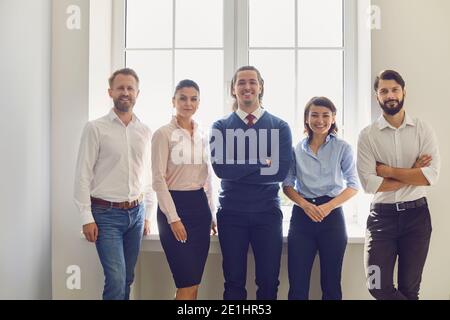 Ritratto di un team di lavoro creativo di successo guardando la fotocamera e sorridendo vicino alla finestra. Foto Stock