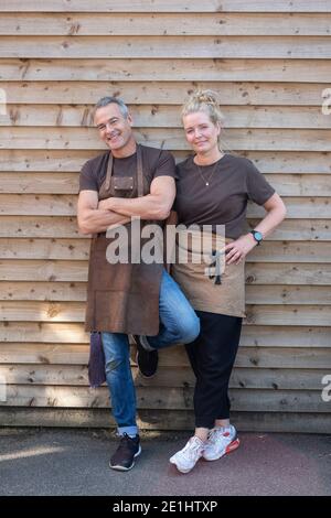 Uomo e donna in grembiule, colleghi che si rompono dal lavoro, ridendo Foto Stock