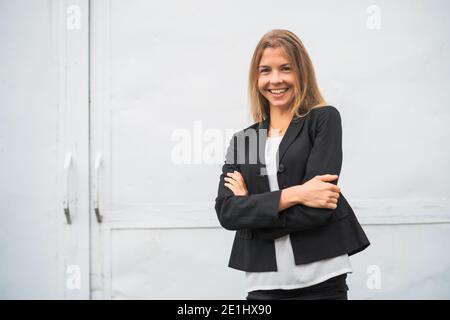 Ritratto esterno di felice donna d'affari moderna. Donna d'affari bionda è in piedi all'aperto e sorridente. Foto Stock