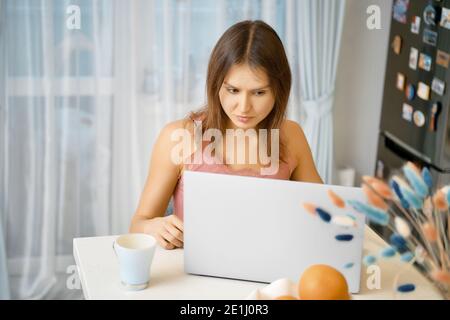 La giovane donna lavora a distanza da casa Foto Stock