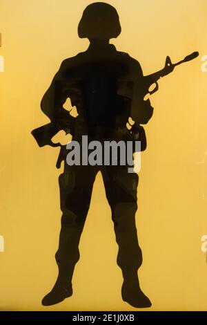 Silhouette di un soldato che indossa un casco e tiene un arma Foto Stock