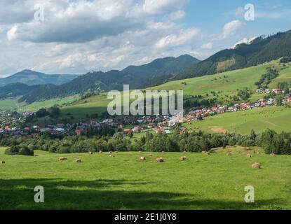 Vista sul villaggio di Liptovska Luzna ai piedi delle montagne di Low Tatra con prati verdeggianti, colline boscose e balle di paglia. Slovacchia, estate sunn Foto Stock