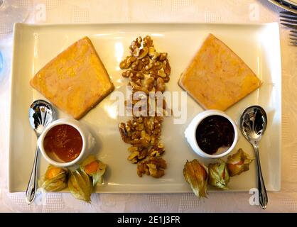 Zeppe di foie gras noci sgusciate acerrimano arancio marmellata rosso marmellata di frutta e kumquat con due cucchiai da portata su un piastra rettangolare in ceramica verde chiaro Foto Stock