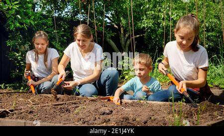 Grande famiglia con bambini che lavorano in casa giardino cortile e. scavando suolo su letto di giardino per piantare vegetali a primavera Foto Stock