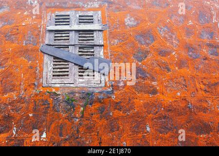 Astratto lichene arancione che cresce su antiche mura di pietra e finestra di legno del tempio di Wat Sampova, Cambogia. Messa a fuoco selettiva. Foto Stock