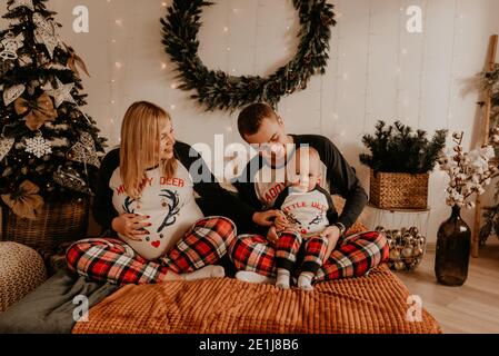 famiglia allegra e felice in pigiama con bambino sdraiarsi sul letto in camera da letto. vestiti di famiglia di nuovo anno sembra outfits. Regali per la festa di San Valentino Foto Stock