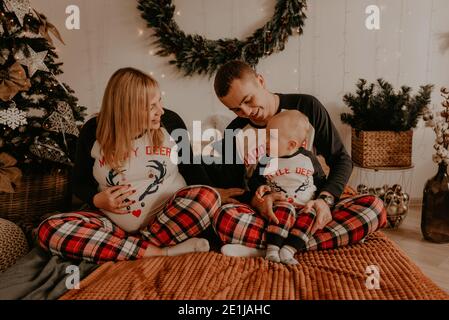 famiglia allegra e felice in pigiama con bambino sdraiarsi sul letto in camera da letto. vestiti di famiglia di nuovo anno sembra outfits. Regali per la festa di San Valentino Foto Stock