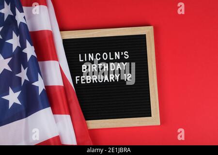 Cartellone nero con testo compleanno di Lincoln e bandiera americana su sfondo rosso. Vista dall'alto spazio di copia piatto Foto Stock