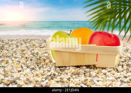 Le mele e le arance confezionate si trovano sulla spiaggia vicino al mare. Foto Stock