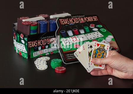 Texas Hold ‘em pokergame in una scatola di metallo per giocare a poker a casa. Carte che tengono mano che mostrano la casa piena con sfondo nero. Copenhagen, De Foto Stock