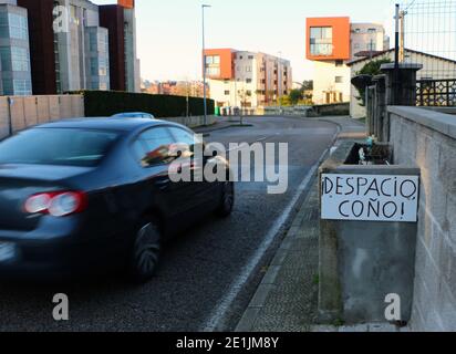 Mano stradale scritto segno in spagnolo chiedendo ai conducenti di rallentare con una macchina che passa rapidamente Santander Cantabria Spagna Foto Stock