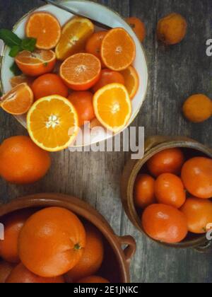 Arance, mandarini, mandarini, tutti gli agrumi in ciotola e su un tavolo da cucina rurale Foto Stock