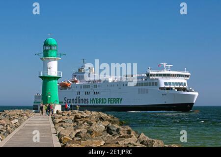 Faro sulla mole del porto e traghetto ibrido M/V Berlino da Scandlines che entra nel porto di Warnemünde, Meclemburgo-Vorpommern, Germania Foto Stock