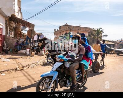 MBOUR, SENEGAL - DICEMBRE CIRCA, 2021. Poche donne e uomini con Corona Virus maschera a piedi, guidando in strada villaggio. Alcuni indossano la maschera, alcuni no. Foto Stock