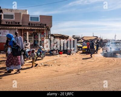 MBOUR, SENEGAL - DICEMBRE CIRCA, 2021. Poche donne e uomini con Corona Virus maschera a piedi nel mercato di strada villaggio. Alcuni indossano la maschera, alcuni no. Se Foto Stock