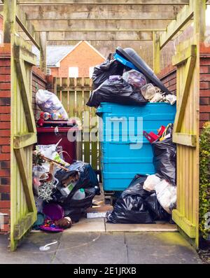 Contenitori pieni e traboccanti, wastbin, trashcan, ricettacolo, rifiuti in un deposito di bidoni residenziale su una tenuta di alloggi del Regno Unito, Inghilterra, Regno Unito. Rifiuti, rifiuti Foto Stock