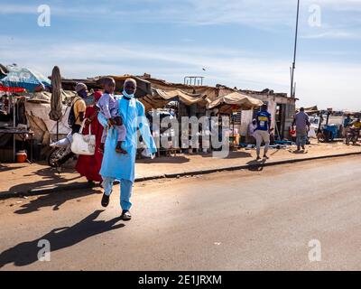 MBOUR, SENEGAL - DICEMBRE CIRCA, 2021. Poche donne e uomini con Corona Virus maschera a piedi nel mercato di strada villaggio. Alcuni indossano la maschera, alcuni no. Se Foto Stock