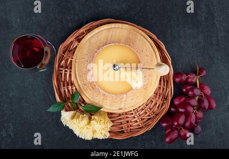 Gustoso formaggio gourmet Tete de Moine, un bicchiere di vino rosso e un mazzo di uve, vista dall'alto, profondità di nitidezza poco profonda Foto Stock