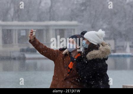 Madrid, Spagna - 07 gennaio 2021: Una giovane coppia prende un selfie con la sua mobilità, nel parco di Buen Retiro a Madrid, nel bel mezzo di una giornata innevata, a due Foto Stock