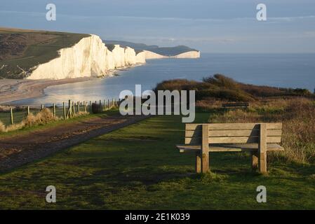 Panchina vuota in legno di fronte alle maestose scogliere bianche Seven Sisters vicino a Seaford, Sussex, Inghilterra, Regno Unito Foto Stock
