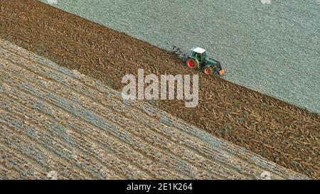 Un coltivatore con un trattore aratura un campo. Vista dall'alto Foto Stock