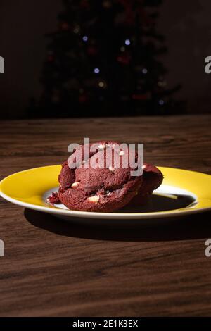 Biscotti di velluto rosso con cioccolato bianco e flasher a natale albero sullo sfondo Foto Stock