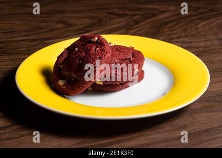 Biscotti di velluto rosso con cioccolato bianco sul tavolo di legno scuro. Foto Stock