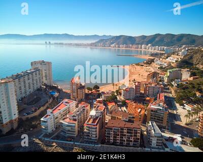 Punto di vista del drone aereo Cullera sabbia vuota spiaggia e tetti del paesaggio urbano durante il sole giorno d'inverno. Località turistica famosa. Provincia di Alicante, Cos Foto Stock