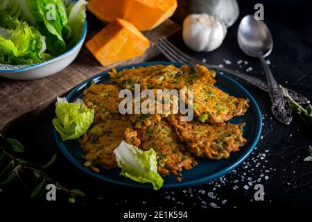 Tortino vegetale con zucca, cipolla e aneto. Frittelle di zucca su sfondo nero. Foto Stock