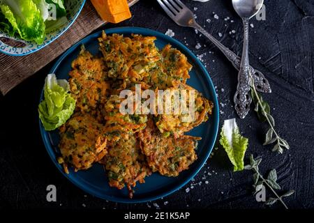 Tortino vegetale con zucca, cipolla e aneto. Frittelle di zucca su sfondo nero. Foto Stock