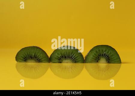 Pezzi di kiwi metà con una tendenza di colore giallo illuminante con un posto per inserire un copyspace. Foto Stock