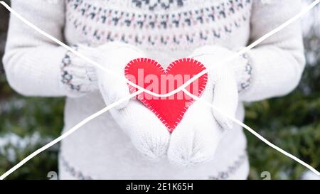 Un divertente schizzo con un contorno di busta sopra una foto con una ragazza che tiene un cuore rosso feltro in mittens in inverno. Concetto di posta di San Valentino. Taglia Foto Stock